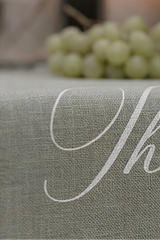 Gray tablecloth with white cursive text, grapes, and figs in the background